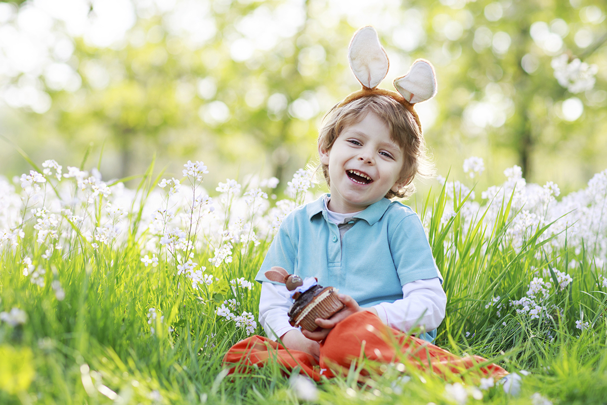 child sitting in grass wearing easter bunny ears